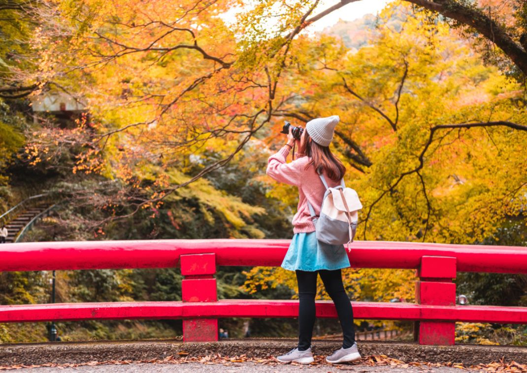 Ung kvindelig rejsende fotograferer det smukke efterår, Japan