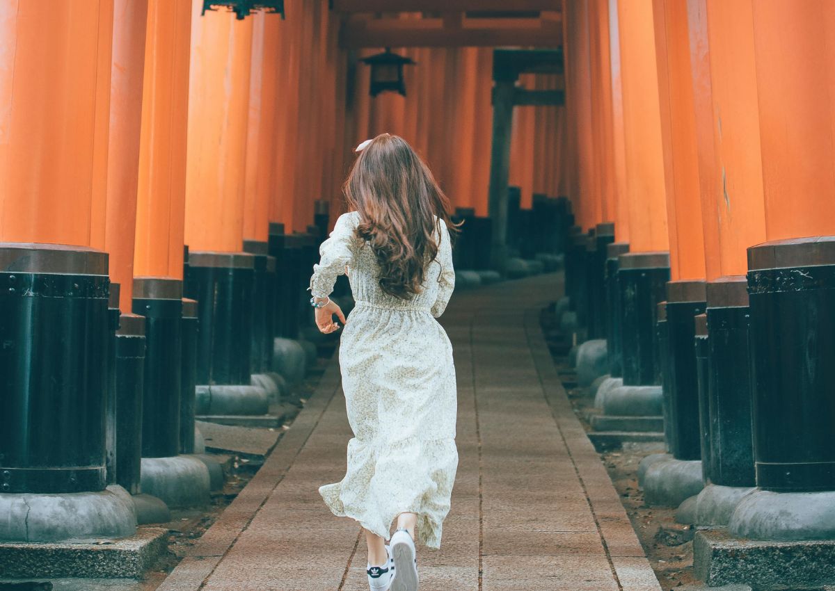 Flicka springer genom Fushimi Inari-helgedomen i Kyoto