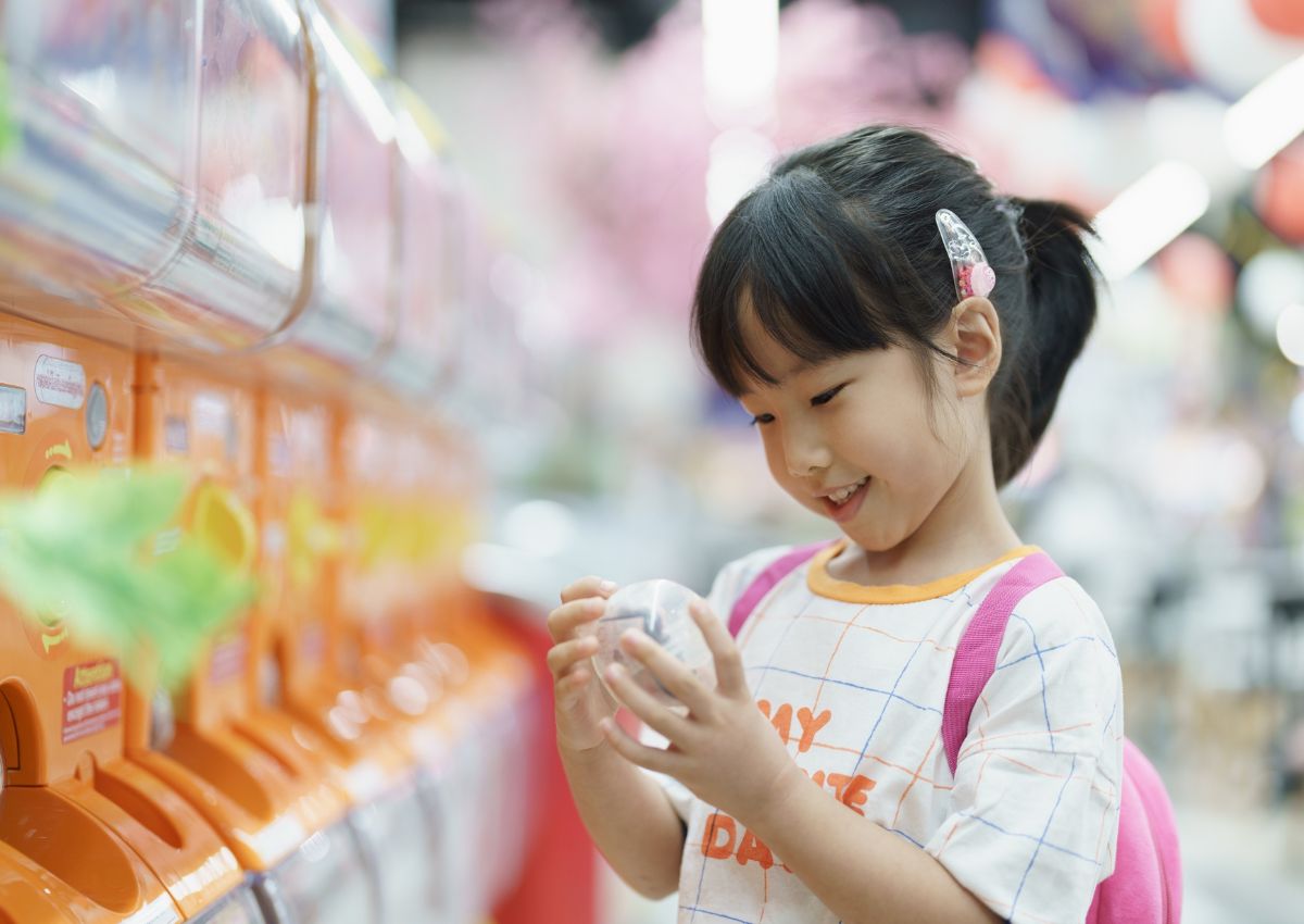Barn provar en japansk gachaponautomat med små leksaker i kapslar.