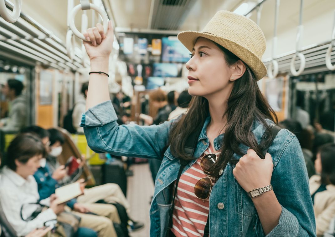 Ung asiatisk kvinnlig resenär står i tunnelbanan i Japan och håller i ett handtag.