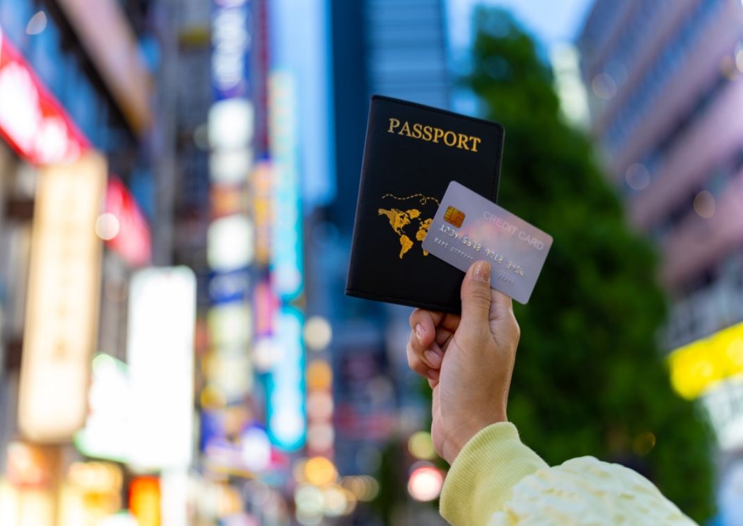 En kvinnas hand håller upp ett pass och ett kreditkort i Tokyo