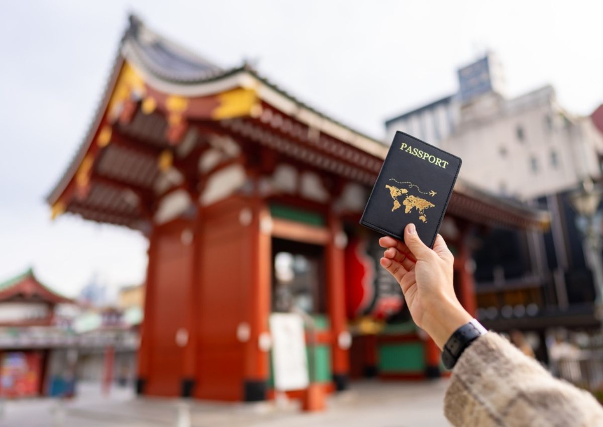 En kvinnas hand håller upp ett pass och ett kreditkort i Tokyo