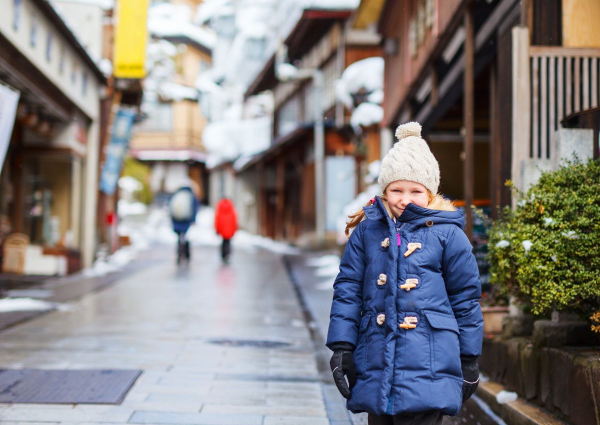 Barn besöker en snötäckt japansk stad med varma källor.