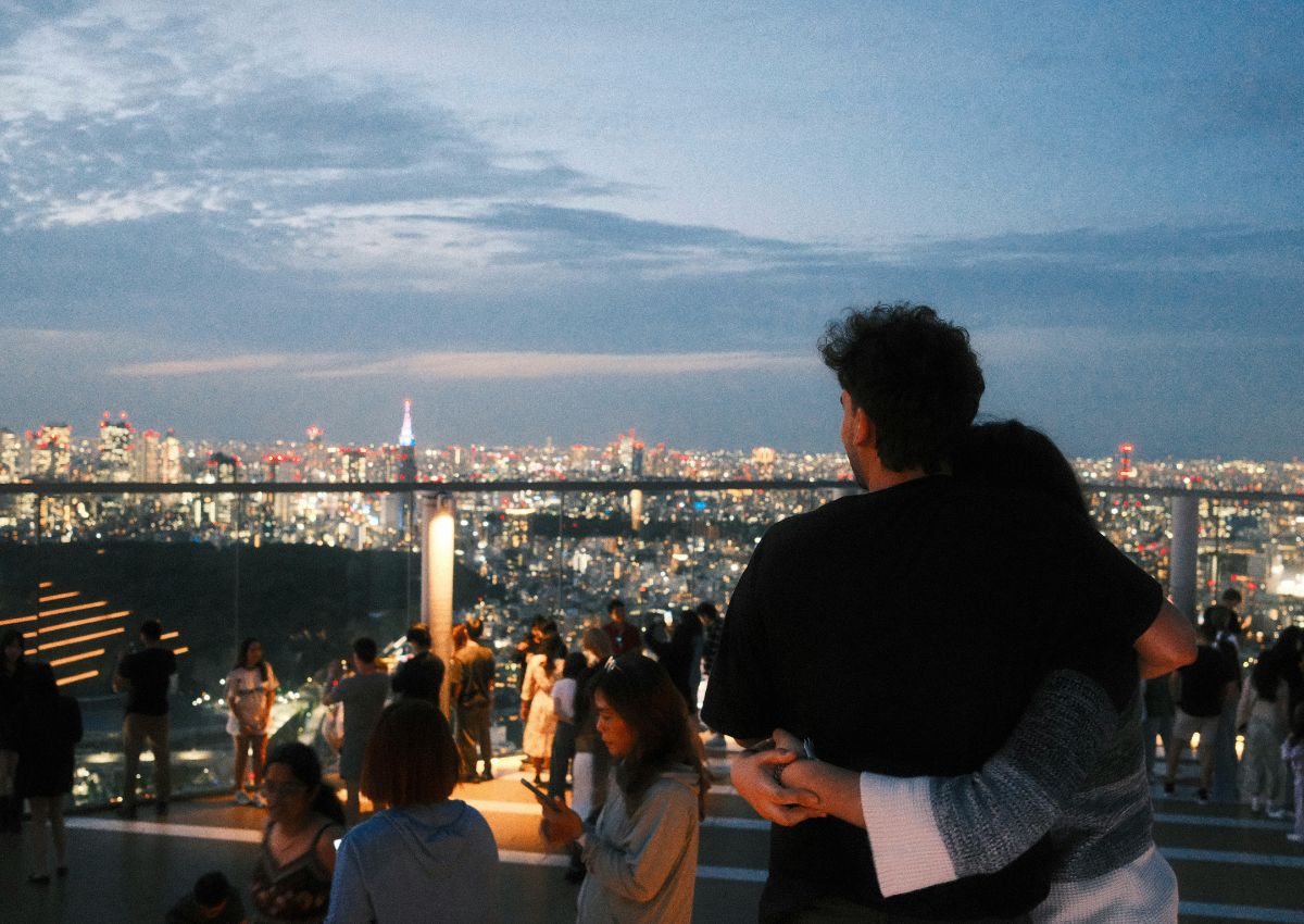 Par blickar ut över Tokyos ljus från Shibuya Sky i skymningen.