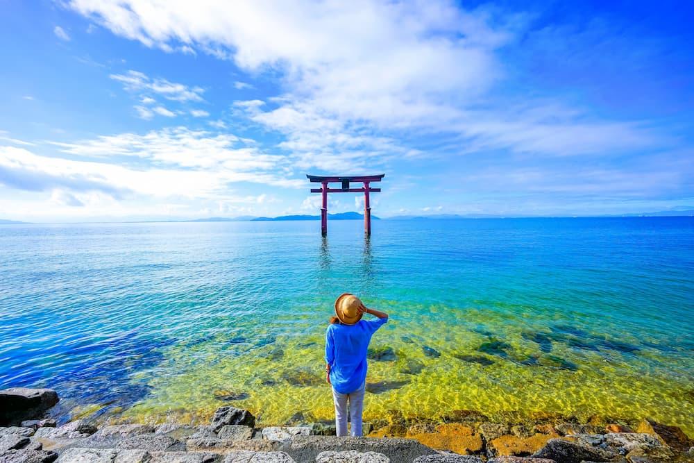 Resenär står nära en torii-port vid Biwa-sjön i Shiga Prefecture, Japan