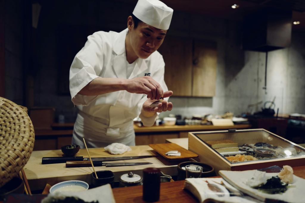 Japansk kock gör sashimi framför bardisken på en japansk sushirestaurang