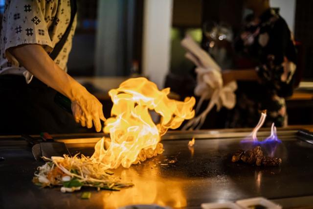 Kock som förbereder teppanyaki-måltid med nötkött och grönsaker