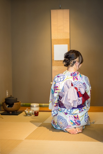 Flicka i yukata i ett traditionellt te-rum