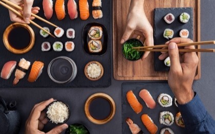 Olika sorters sushi, inklusive nigiri, sashimi och rullar, som delas och äts med ätpinnar