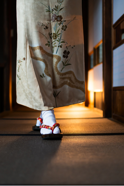 Kvinna i kimono går genom ett traditionellt ryokan med tatamimattor och shoji-dörrar
