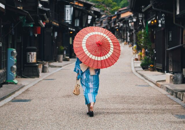 Kvinna i kimono promenerar genom historiska Naraijuku, Japan.