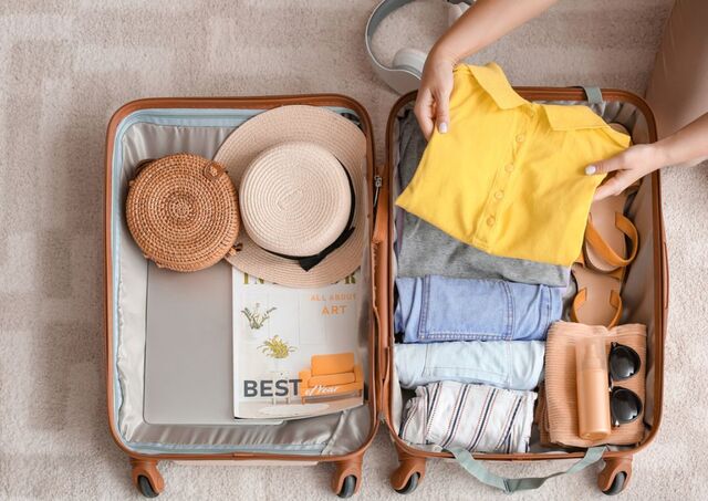Kvinna packar en gul skjorta i en resväska inför en resa till Japan. 